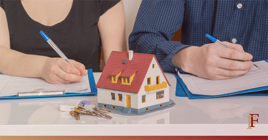 image of two people signing documents with a toy house between them