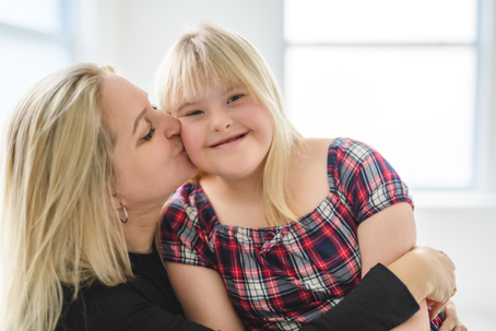 mother kissing daughter on the cheek