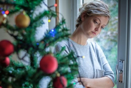 woman contemplating next to Christmas tree