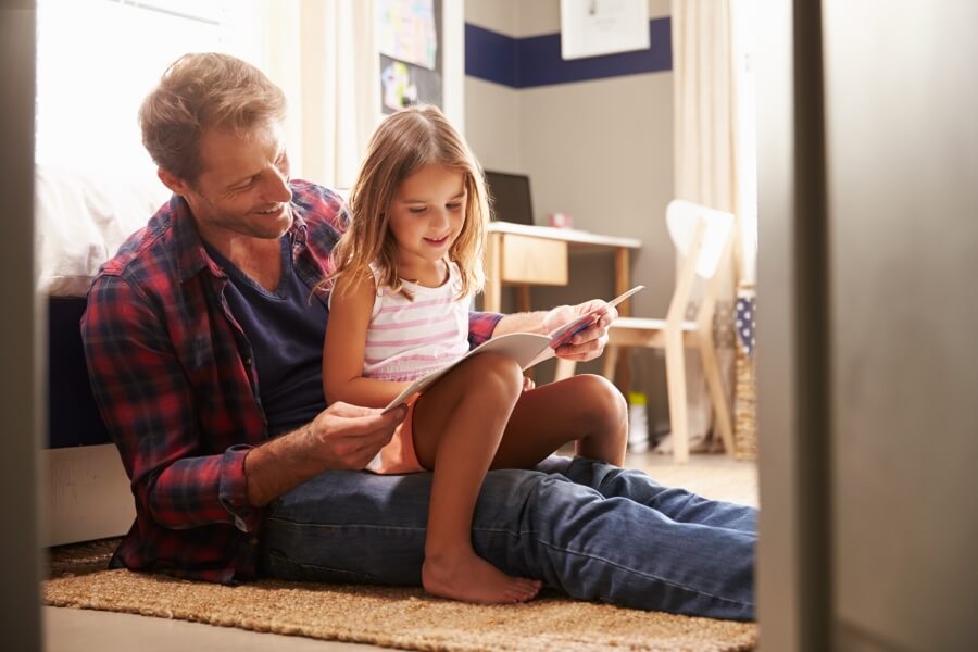 a father with child visitation rights reads a book to his young daughter