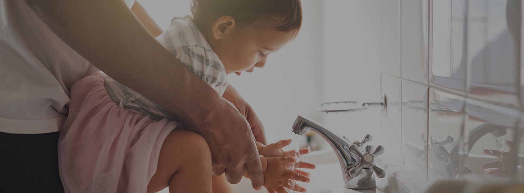 A parent helping their small child wash their hands
